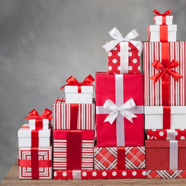 Hermosa montaña de cajas con regalos y arcos en un fondo gris — Foto de Stock