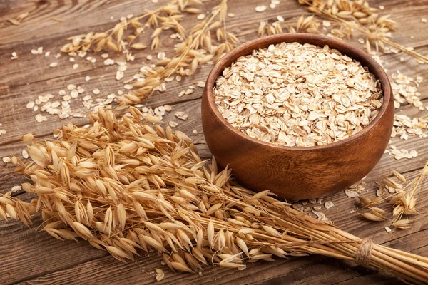 Oat flakes in a bowl on the old board. — Stock Photo, Image