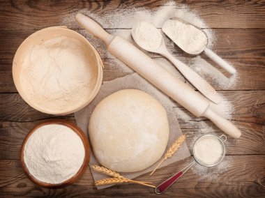 Dough and rolling-pin on wooden table. clipart