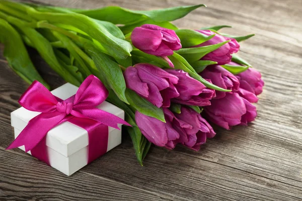 Tulipanes y caja de regalo en el tablero . — Foto de Stock