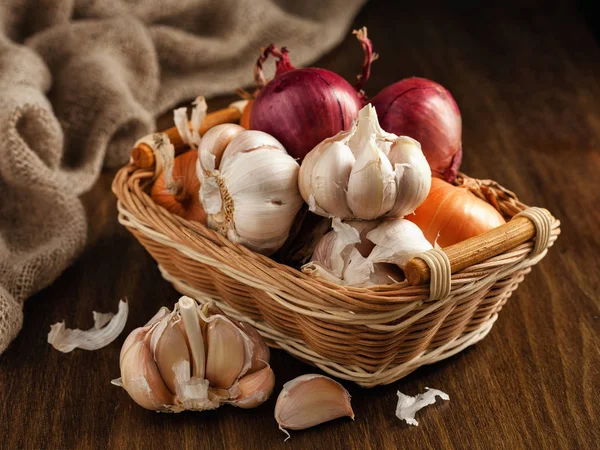 Zwiebeln und Knoblauch in einem Korb auf dem Tisch — Stockfoto