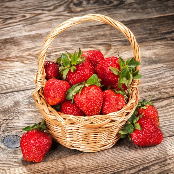 Fresas maduras en una canasta sobre una mesa vieja — Foto de Stock