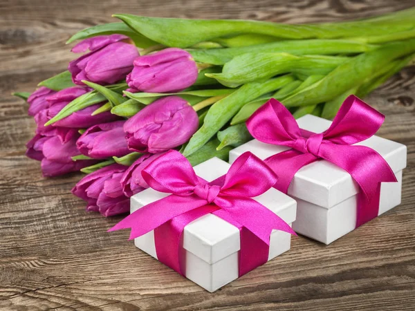 Tulpe, Geschenkschachteln mit violetten Schleifen auf Holzbrett — Stockfoto