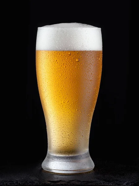 Φρέσκια μπύρα σε ποτήρι σε μαύρο φόντο. — Φωτογραφία Αρχείου