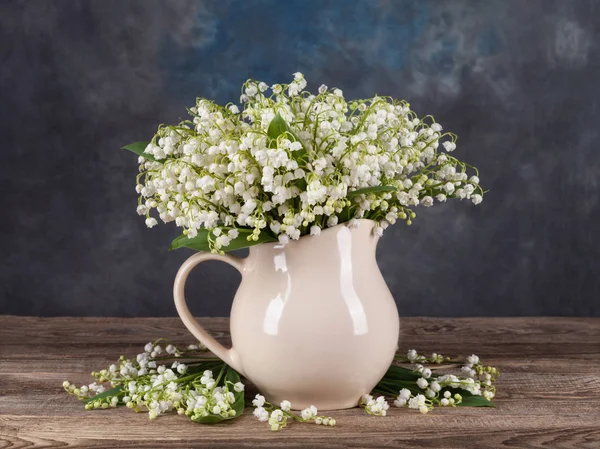 Lilies of the valley in vase on old board — Stock Photo, Image