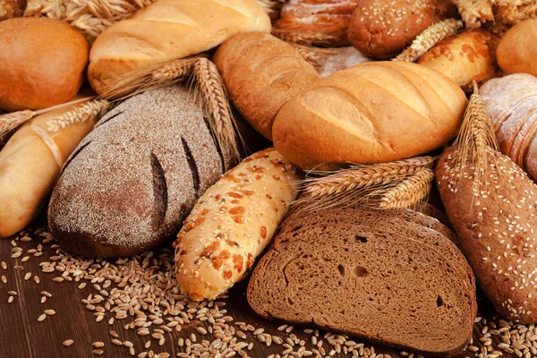 Brotsortiment und Weizenähren auf dem Tisch — Stockfoto
