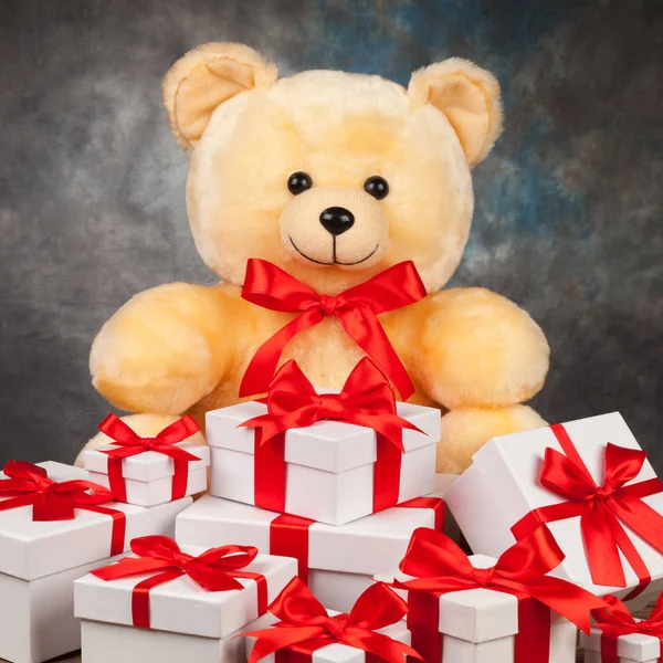 Teddy bear and white boxes with gifts on the old board