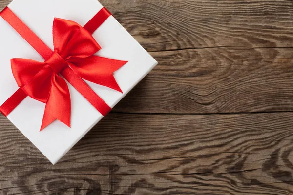 White box with a red bow on the old board.