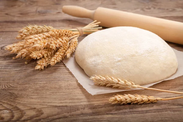 Dough, spikelets and rolling pin on an old board — Stock Photo, Image