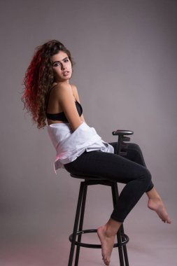 Studio gri bir arka plan üzerinde siyah kıvırcık saçlı oldukça ince kız