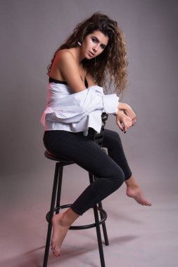 Studio gri bir arka plan üzerinde siyah kıvırcık saçlı oldukça ince kız