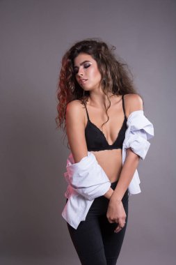 Studio gri bir arka plan üzerinde siyah kıvırcık saçlı oldukça ince kız