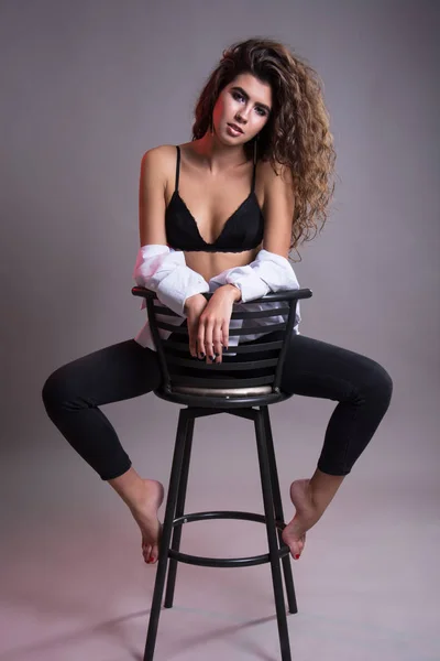 Studio gri bir arka plan üzerinde siyah kıvırcık saçlı oldukça ince kız