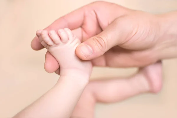 Pies de bebé en la mano de papá con un fondo borroso — Foto de Stock