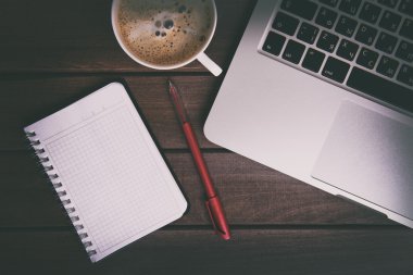 Dizüstü bilgisayar, kahve fincanı ve ahşap masa üstünde defter