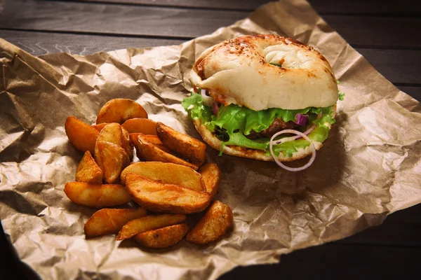 Hamburger und Kartoffelkeile auf Holztisch — Stockfoto