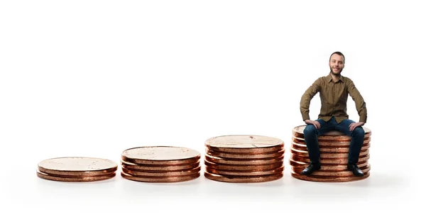 Mężczyzna siedzący na stos monet. — Zdjęcie stockowe