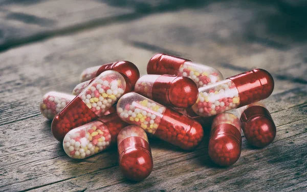 Rode capsules op houten tafel — Stockfoto