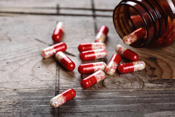 Garrafa de pílula e cápsulas na mesa de madeira — Fotografia de Stock