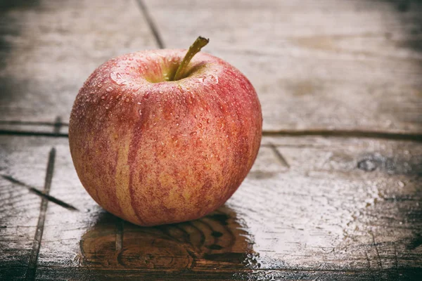Molhado maçã vermelha fresca no fundo de madeira — Fotografia de Stock