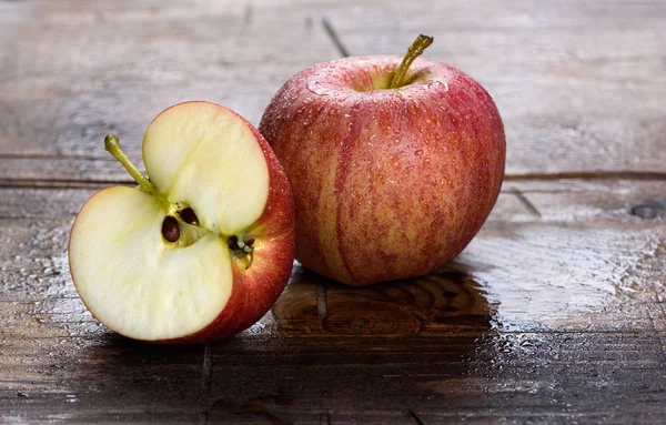 Manzana roja fresca mojada sobre fondo de madera — Foto de Stock