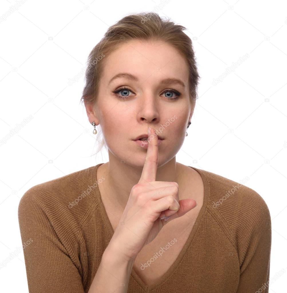 Young woman keeping her forefinger by lips