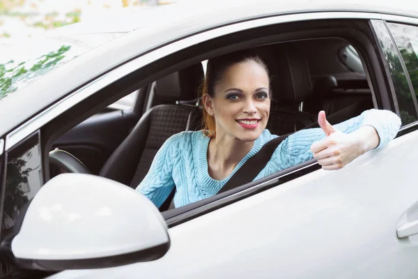 Glad tjej som kör bil och visar tummen — Stockfoto