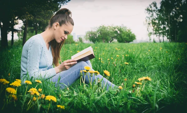 Giovane donna caucasica che legge un libro all'aperto — Foto Stock