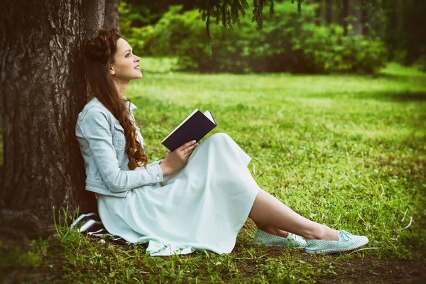 Bella giovane donna che legge un libro nel parco — Foto Stock