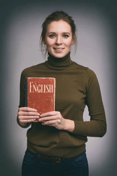 Söt flicka innehar en engelsk lärobok — Stockfoto
