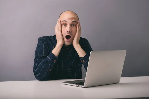 Sorprendido hombre se sienta detrás de un ordenador portátil —  Fotos de Stock