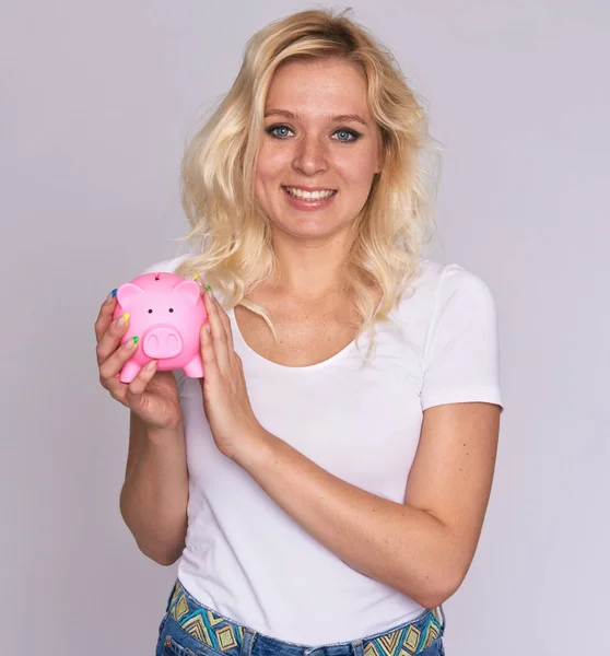 Glückliche Frau mit Sommersprossen hält ein Sparschwein — Stockfoto