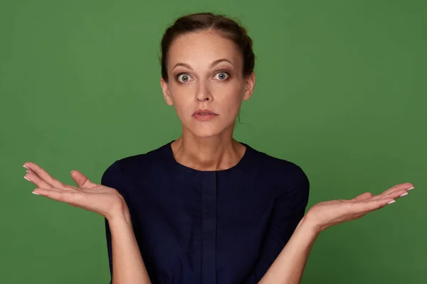 Vrouw schouderophalend haar handen geïsoleerd op groen — Stockfoto