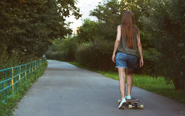 Beautiful young girl riding longboard — Stock Photo, Image