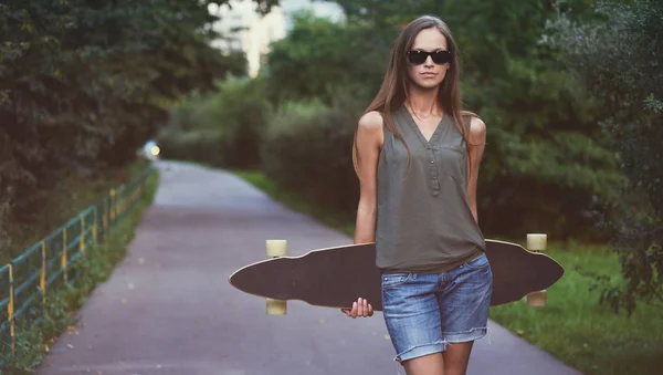 Beautiful young woman with a skateboard — Stock Photo, Image