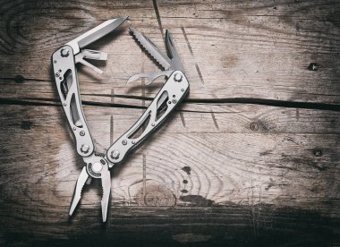stanless steel multitool on wooden background clipart
