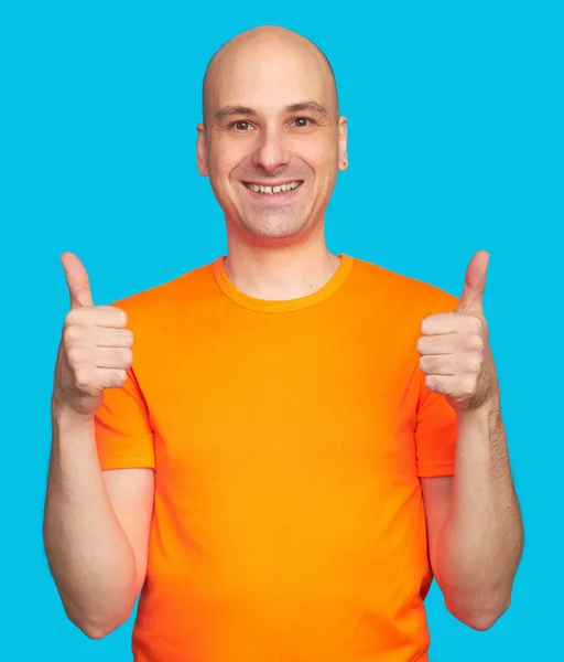 Łysy mężczyzna w jasny pomarańczowy koszula pokazuje kciuki w górze — Zdjęcie stockowe