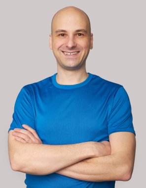 Mavi t-shirt giyen gülümseyen kel adam