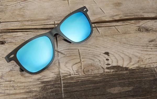 Occhiali da sole blu su uno sfondo di legno — Foto Stock
