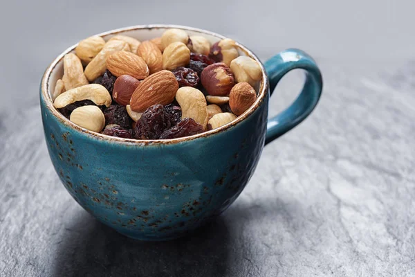 Rosinen und Nüsse in einer Tasse auf einem Steintisch — Stockfoto