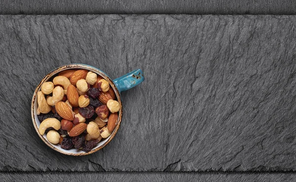 Verschiedene Nüsse in einer Tasse auf Schiefertafel. Ansicht von oben — Stockfoto