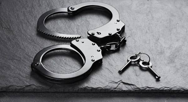 Black Metal handcuffs on stone background — Stock Photo, Image