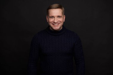 Siyah arka planda mutlu orta yaşlı bir adam