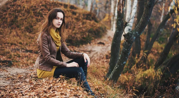 Donna è seduta su un'erba nel parco autunnale — Foto Stock