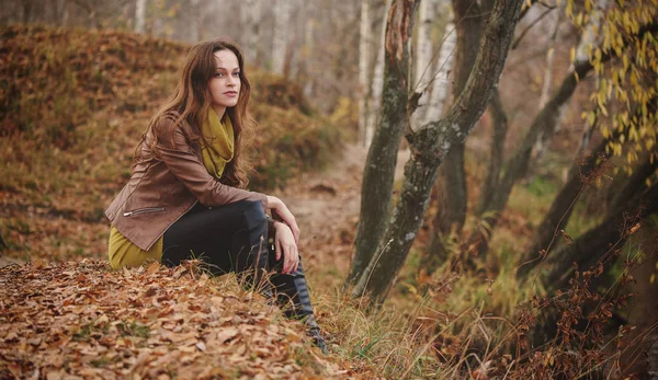 Donna è seduta su un'erba nel parco autunnale — Foto Stock