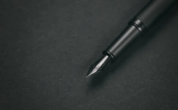Siyah kağıdın üzerindeki eski dolma kalem. — Stok fotoğraf