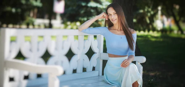 Beautiful woman is sitting on a bench in the park — Stock Photo, Image