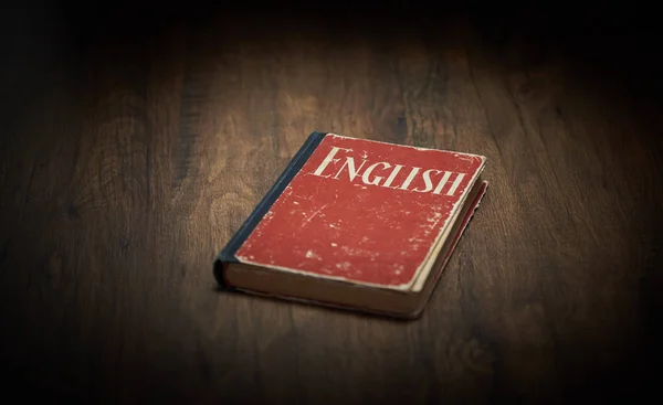 Livro didático de inglês vermelho em uma mesa de madeira — Fotografia de Stock