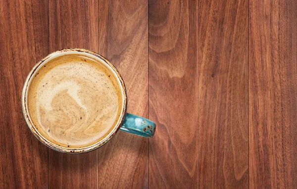 Šálek kávy s mlékem na pozadí dřevěného stolu — Stock fotografie