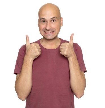 40 yaşında, tişörtlü kel bir adam beyazın üzerinde baş parmak gösteriyor.